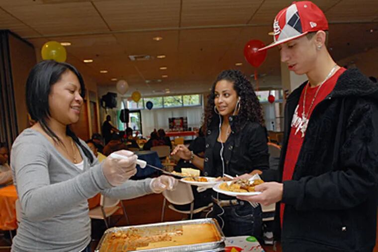 At Camden County College's Camden city campus, a Hispanic Expo in honor of Spanish Heritage Month, including singing, dancing and lots of Hispanic food. Here, Hoanh Thach, left, dishes out food for Millivett Jimenez and James Zamora; all three are Camden County college students. (April Saul / Staff Photographer)