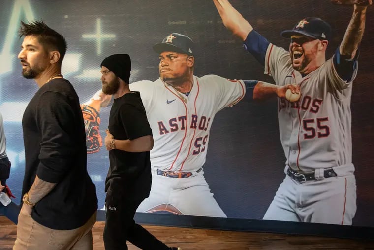 Nick Castellanos (left) and Bryce Harper of the Phillies walk by an Astros mural at Minute Maid Park, site of Games 1 and 2 of the World Series.
