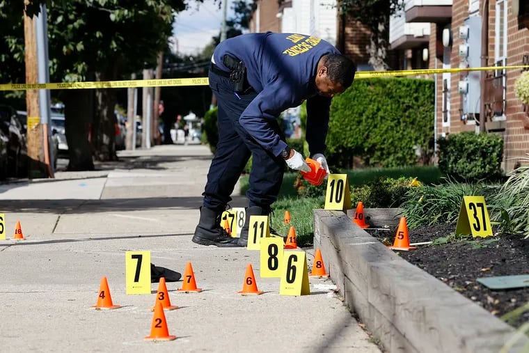 A Philadelphia Police Crime Scene investigator places evidence markers outside a unit at the West Poplar Apartments along North 13th and Wallace Streets after a male was fatally shot on Monday, September 26, 2022.