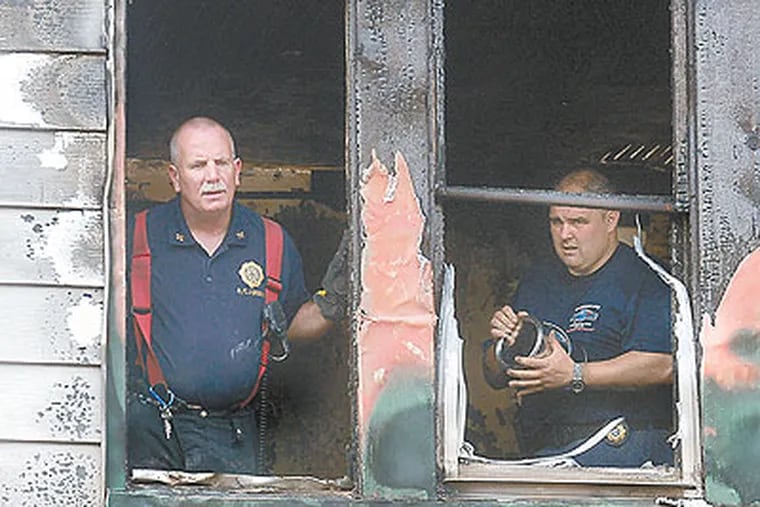 Fire Chief John Gribbin, left, looks out of the Vine Street house destroyed by an overnight fire on Thursday in Trenton. Gribbin found and rescued a child. (AP Photo / The Trentonian, Gregg Slaboda)