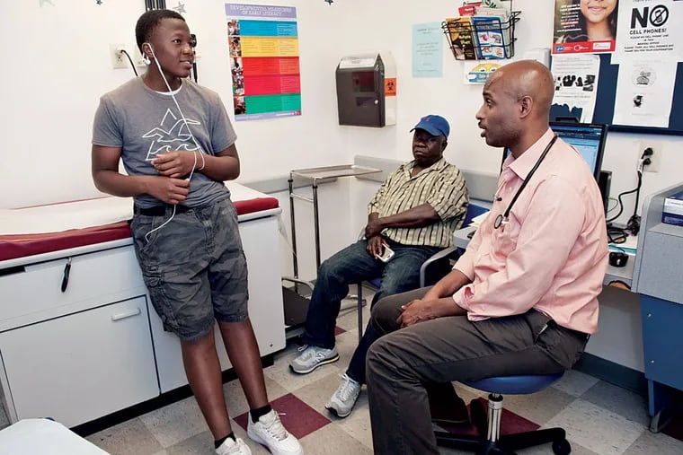 Pediatrician Roy Wade Jr. (right) talks with Jurtomu Vesslee, 14, and his father, David, at the Cobbs Creek office of Children's Hospital. MICHAEL PRONZATO / Staff Photographer