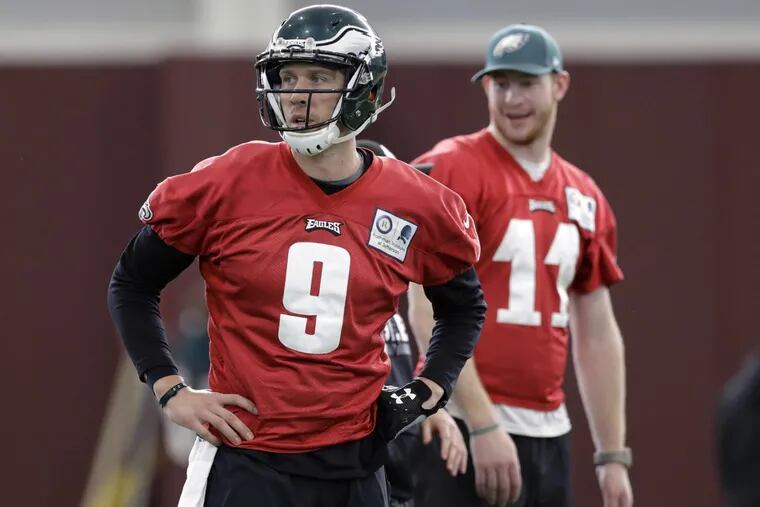 Injured Philadelphia Eagles quarterback Carson Wentz (11) looks on as quarterback Nick Foles (9) takes part a practice for the NFL Super Bowl 52 football game Thursday, Feb. 1, 2018, in Minneapolis. Philadelphia is scheduled to face the New England Patriots Sunday. (AP Photo/Eric Gay)