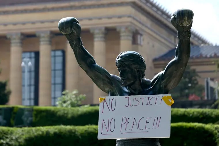 A sign hangs on the Rocky statue after a protest against the Minneapolis police custody death of George Floyd in June 2020. The statue is a focus of a new podcast series.