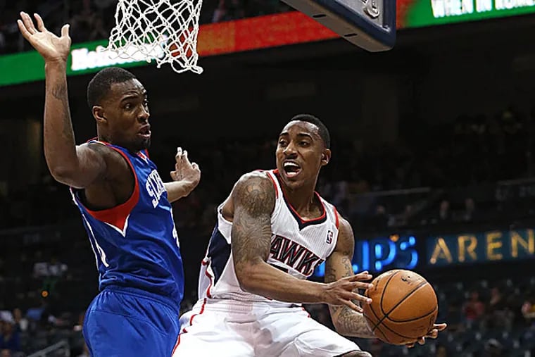 Hawks guard Jeff Teague looks to pass under the defense of 76ers forward Jarvis Varnado in the first half. (Jason Getz/AP)