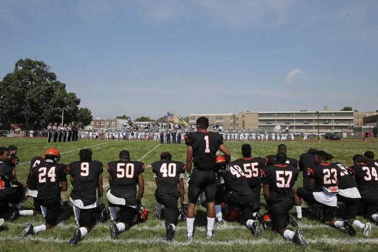 Woodrow Wilson High's Edwin Lopez (#1) stands while some of his teammates kneel during the national anthem before their game against Highland High School on Saturday, September 10, 2016.