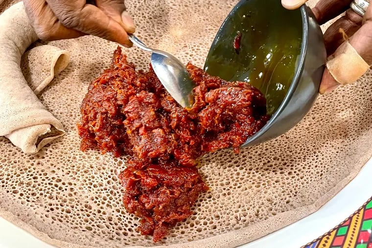 An Ethiopian kitfo of raw minced beef seasoned with spices and aromatic butter is served atop injera bread at Amsale Cafe in West Philadelphia.