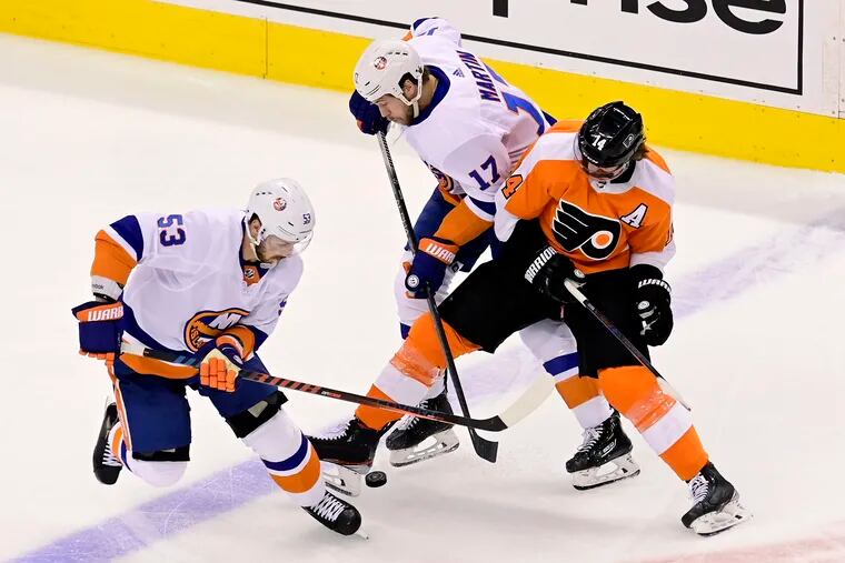Flyers center Sean Couturier (14) tries to hold onto the puck under pressure from the New York Islanders' Casey Cizikas (left) and Matt Martin in the second period Tuesday. Couturier later left with an injury.