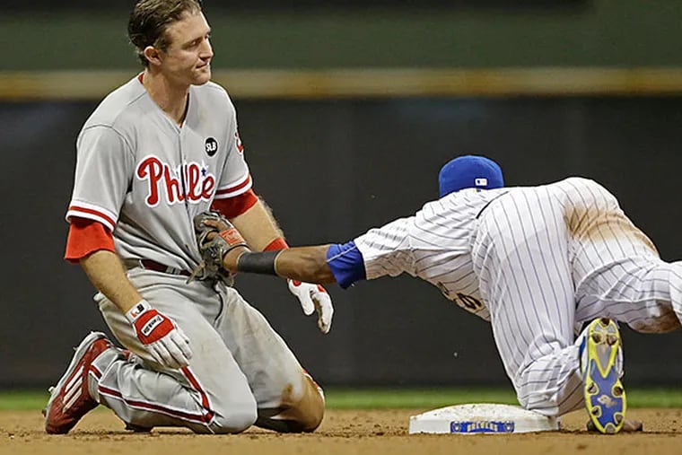 Milwaukee Brewers' Jean Segura, right, dives to tag out Philadelphia Phillies' Chase Utley, left, who over slid second base during the seventh inning of a baseball game Friday, Aug. 14, 2015, in Milwaukee.
