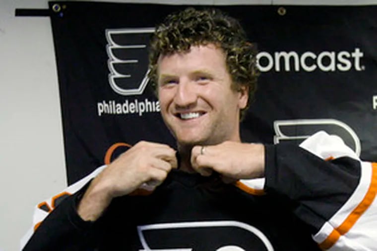 Scott Hartnell tries on his new Flyers jersey during a news conference in Voorhees. He signed with the team last month.