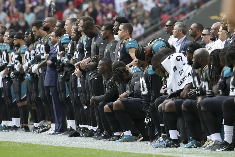 In this Sept. 24, 2017 photo, Jacksonville Jaguars NFL football players are shown, some standing an some kneeling, during the playing of the national anthem before an NFL football game against the Baltimore Ravens at Wembley Stadium in London.