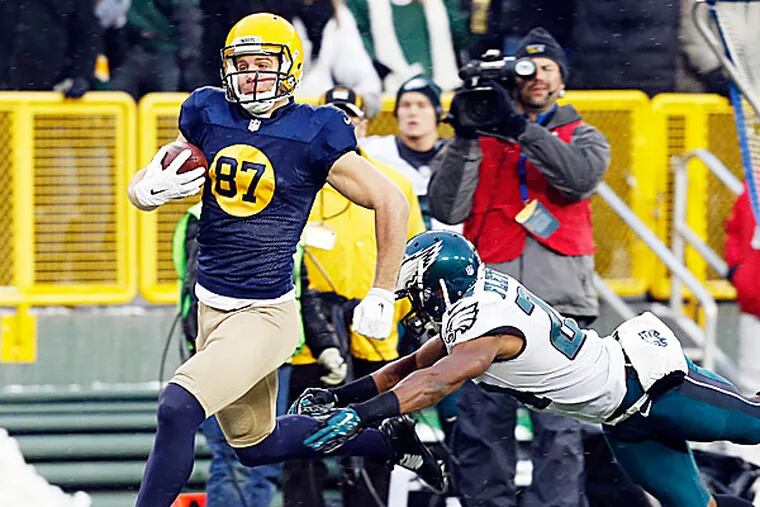 The Eagles' Bradley Fletcher trips up the Packers' Jordy Nelson after a 64-yard pass reception during the first half. (Mike Roemer/AP)
