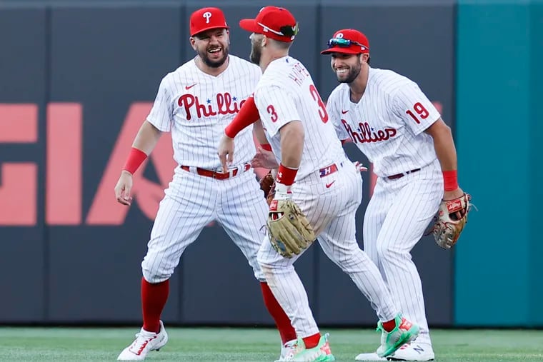 Phillies outfielders Kyle Schwarber, Bryce Harper and Matt Vierling celebrate their 9-5 opening-day win over the Athletics on Friday.