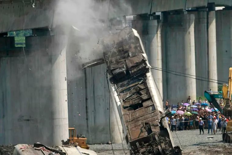 Workers remove a derailed train car from a bridge after the crash that killed 40 people in Wenzhou, China, in July.