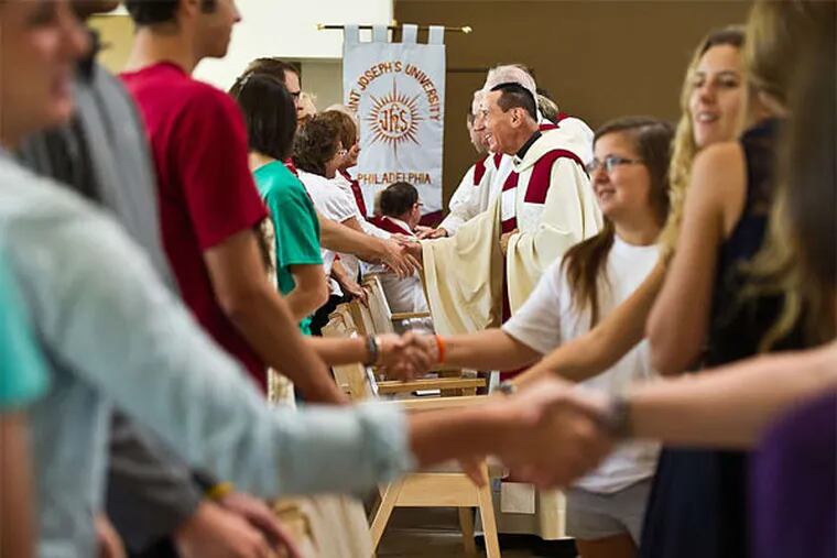 PHOTOS: ST. JOSEPH'S UNIVERSITY Young Hawks exchange the sign of peace at the Mass of the Holy Spirit earlier this month.