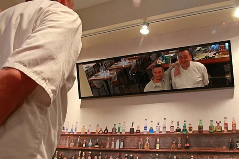 Restaurant Neuf owners Bob Moysan (left) and Joncarl Lachman are reflected in a mirror over a small bar at their South Philadelphia restaurant. ( Michael Klein / Philly.com )