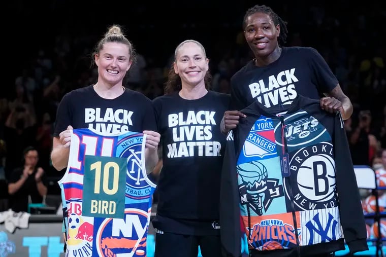 Seattle Storm guard Sue Bird, center, poses for a photo with former Storm teammates, New York Liberty forward Natasha Howard, left, and guard Sami Whitcomb during a presentation before a WNBA basketball game.