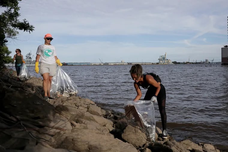 Jana Mars, of right, of Aqua Vida, and Carol Muracco, center, of the Ike Foundation, pick up trash during a Delaware Watershed cleanup in Philadelphia, PA on June 12, 2019. 34 volunteers removed 1248.5 lbs from the area around the Chart House.