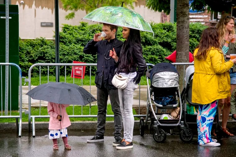 Andrey (left) and Shiran Lunov of Fairmount, with daughter Stephanie, 2, endure the rain in Center City on Sunday. 
