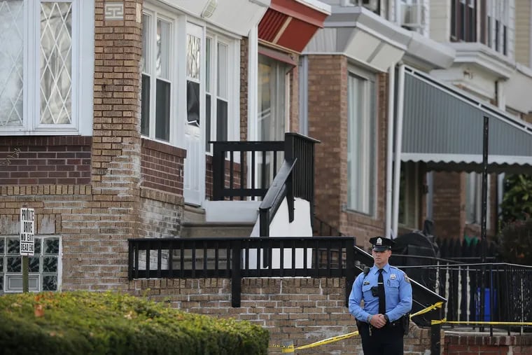 A police officer stands outside the house on 5700 block of Haddington Lane in Overbrook where a 19-year-old man allegedly killed his 11-year-old brother in an accidental shooting.