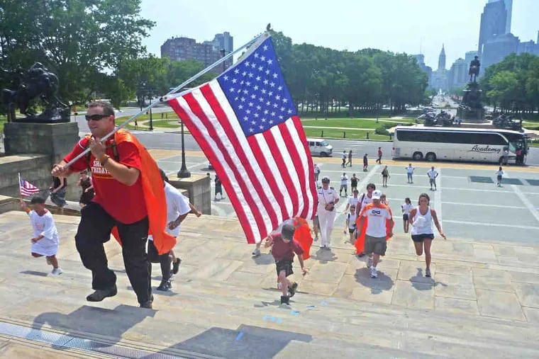 Carrying an American flag, Troy Yocum runs up the Rocky steps at the Philadelphia Museum of Art, followed by 30 supporters. &quot;We made it,&quot; he said of the climb. Now, it's on to Boston.