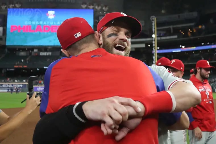 Slugger Bryce Harper (middle right) and pitcher Zack Wheeler embraced after the Phillies clinched a spot in the MLB playoffs Monday night.