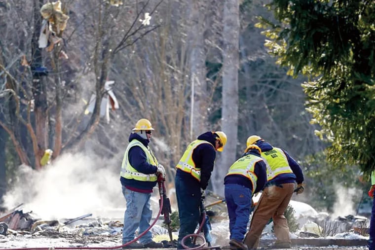 New Jersey Natural Gas personnel dig in front of smoldering debris after a natural gas explosion leveled a house in Stafford on Tuesday, Feb. 24, 2015. (AP Photo/Rich Schultz)