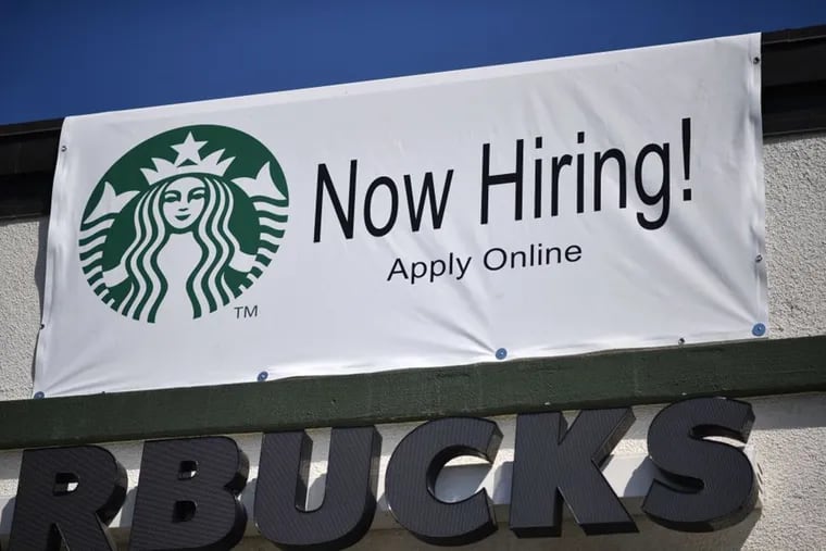 A "Now Hiring" sign is displayed outside a Starbucks drive-thru coffee shop in Glendale, Calif.