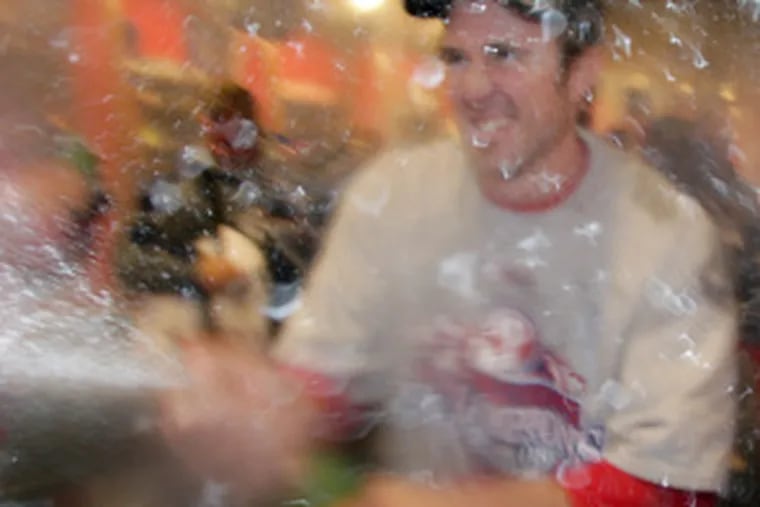 Chase Utley sprays champagne throughout the locker room.