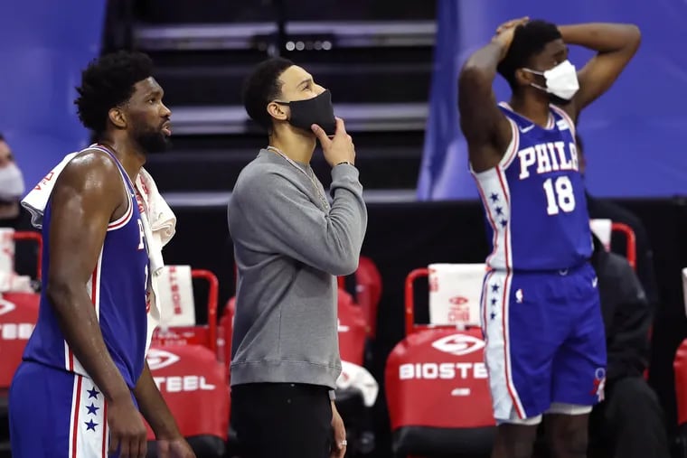 Joel Embiid (left), Ben Simmons (center) and Shake Milton of the SIxers look up toward the scoreboard late in the game against the Trail Blazers.
