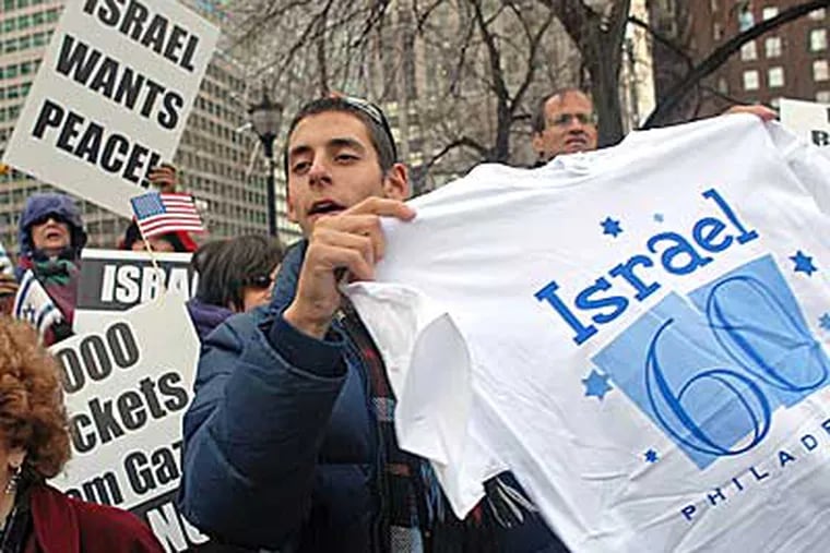 Aaron Smerling, 19, with Adath Jeshurn in Elkins Park hands
out free T-shirts in LOVE Park before the start of" We Stand with
Israel Solidarity Rally."  (Tom Gralish  /  Staff Photographer)