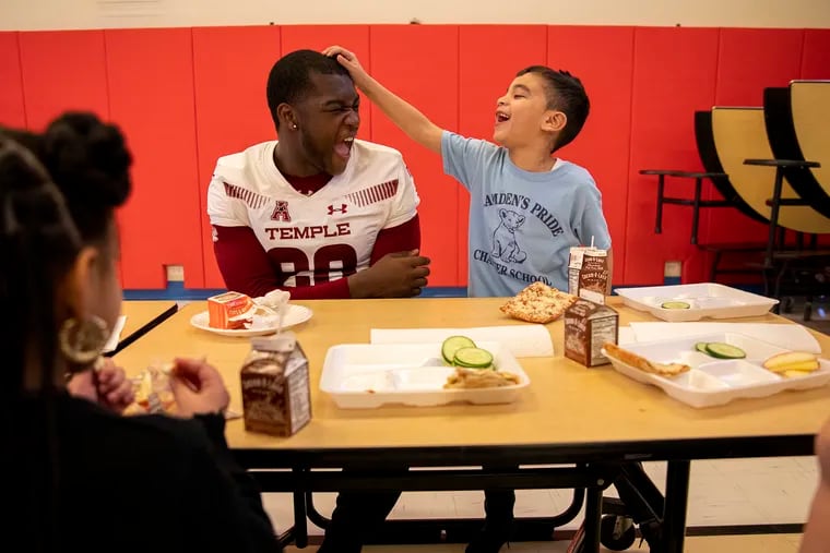 Temple University football running back Onasis Neely laughs with kindergartner Jeremy Petthyng during lunch at Camden Promise Charter School. “It honestly feels good,” Neely said. “I really like giving back, and it’s really nice to work with them. If I was their age I would like to work with someone I could look up to.”