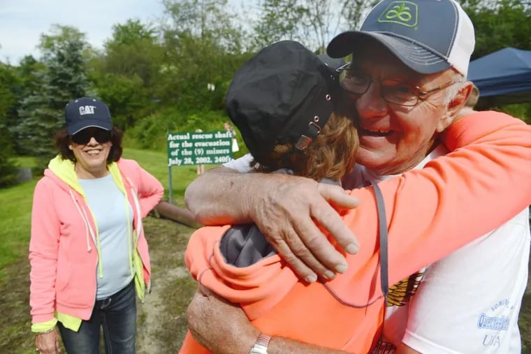 John Unger (right), one of nine miners rescued from the Quecreek mine in 2002, receives a hug from Linda Buterbaugh of Commodore as her friend Rose Ann Buterbaugh looks on during the Quecreek Community Celebration Day Saturday.