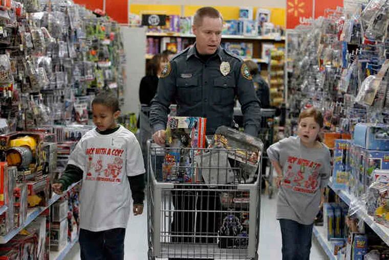 Coatesville City Police Detective Gerald Pawling shops for toys with Marquis Olinick (left), 8, and his daughter Olivia, 7, at the Wal-Mart store in Parkesburg.