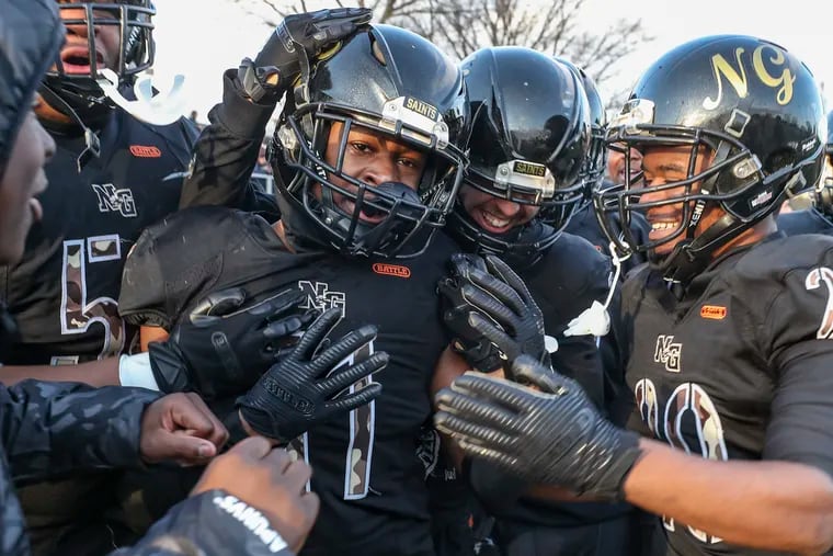 Qaasim Major (11) of Neumann Goretti is surrounded by teammates following his touchdown catch to win a state semifinal against Wyomissing.