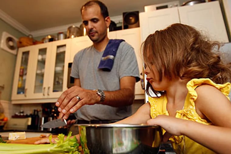 Home chef Chris Jelepis and his daughter Cia, at right, prepare vegetables in their kitchen in South Philadelphia. ( DAVID MAIALETTI  / Staff Photographer )