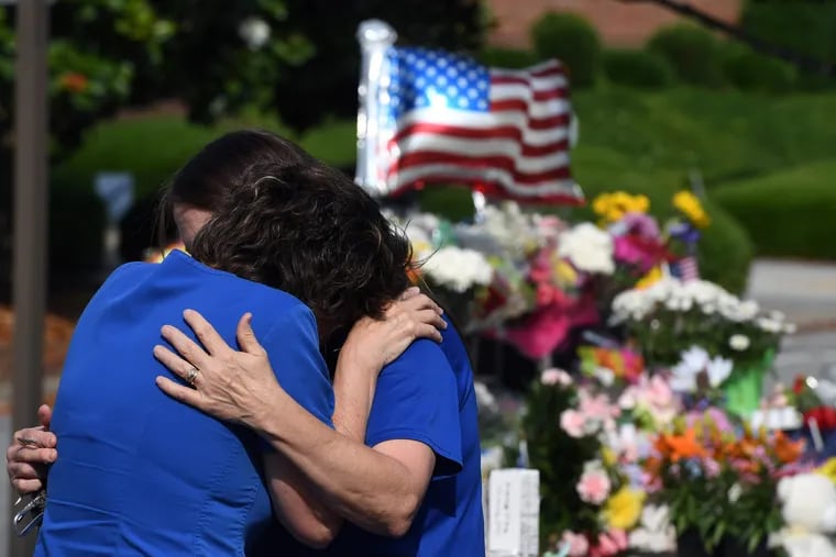 Elaine West-Watson, left, is comforted as she visits a makeshift memorial near the Virginia Beach, Virginia, municipal center on Monday. Twelve were killed in a mass shooting at the municipal center on Friday.