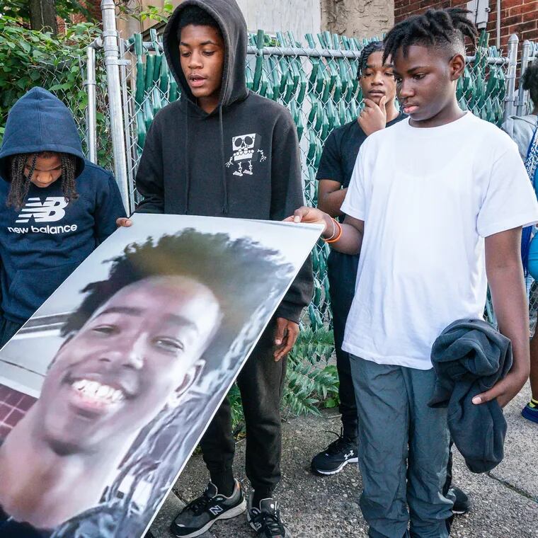 (Left to Right) Shane Norris, 12, second from left, Dayvon Forrest, 13, and Jaalil Elliott, 14, hold a photograph of Hezekiah Bernard at a balloon release for the 12-year-old who was shot and killed and left in a dumpster in West Philadelphia.