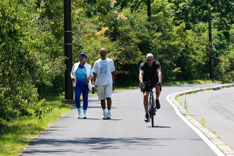 Walkers and a biker use the newly paved recreation path on Martin Luther King Drive on Friday.