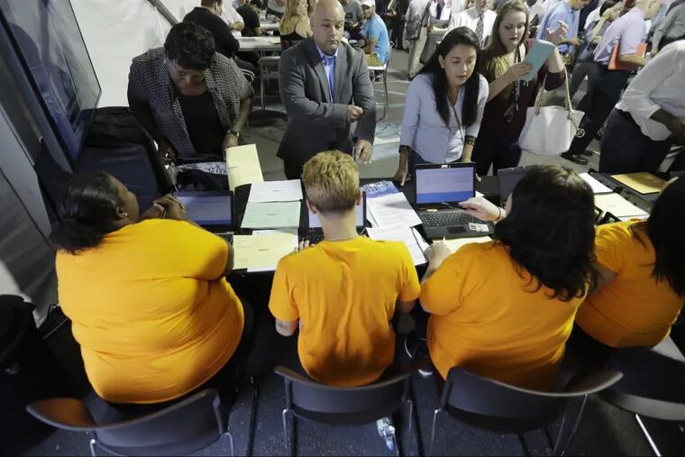 FILE – In this Wednesday, Aug. 2, 2017, file photo, job candidates are processed during a job fair at the Amazon fulfillment center in Robbinsville Township, N.J. The U.S. economy had another strong showing in December, adding 148,000 jobs. The labor market is tightening.