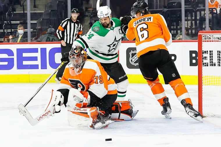 Flyers goaltender Carter Hart stops the puck with teammate defenseman Travis Sanheim against Dallas Stars left wing Jamie Benn during the second period on Monday.