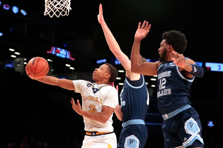 Jhamir Brickus (left) of La Salle scores as Rhode Island's Rory Stewart (center) and Jeremy Foumena defend during the Atlantic 10 tournament on Tuesday at the Barclays Center. Brickus finished with a team-high 18 points.