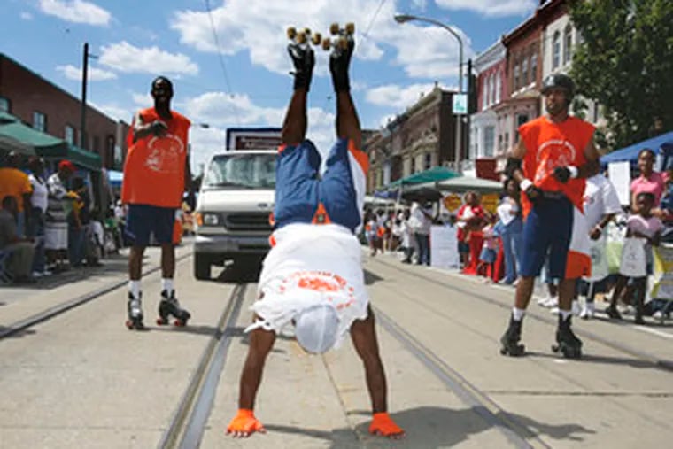 Wayne &quot;Shorty&quot; Morris goes upside down as he and other Wizards on Wheels perform on Baltimore Avenue at the 18th Neighborhood-to-Neighborhood Street Festival and parade.