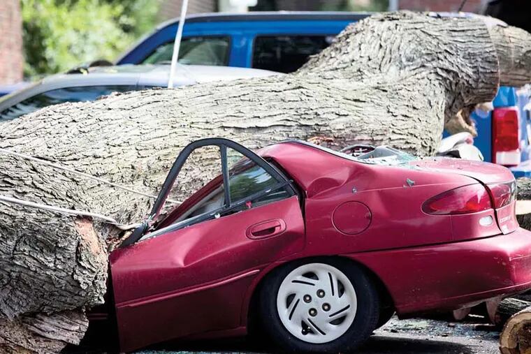 A downed tree lays atop a crushed car Wednesday, July 9, 2014, in Philadelphia. About 228,000 homes and businesses across Pennsylvania remain without power after severe thunderstorms raced across the state.  (AP Photo/Matt Rourke)