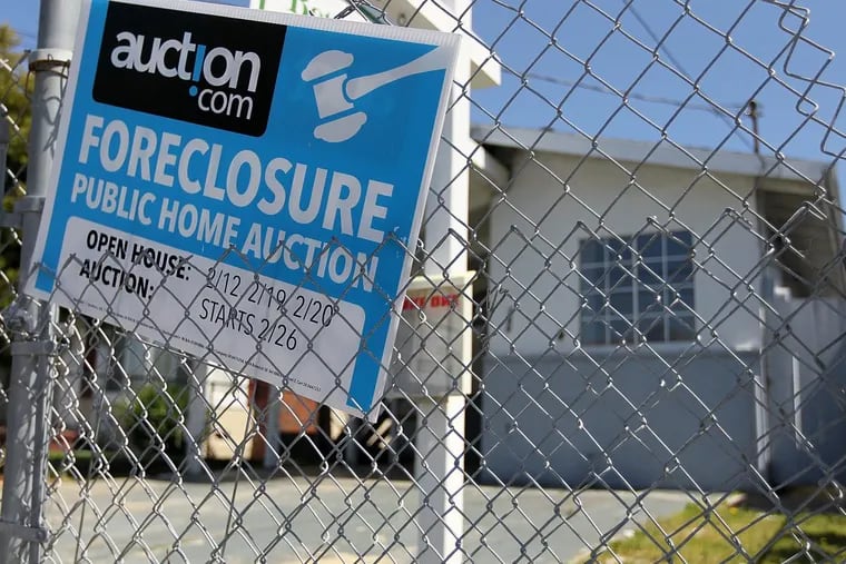 A foreclosure sign hangs on a fence in front of a foreclosed home in California.