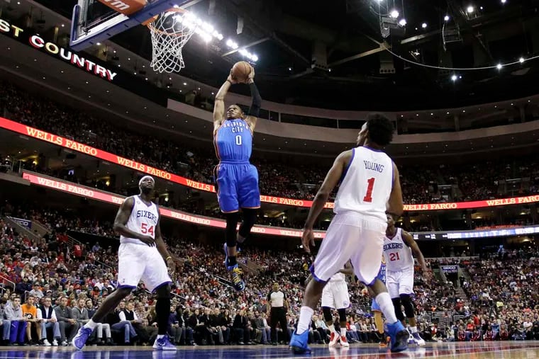 Russell Westbrook, dunking between Kwame Brown and Nick Young (right), has registered six triple-doubles in his career against the Sixers.
