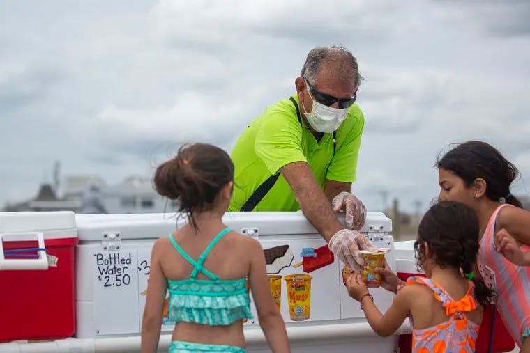 A man hands a little girl a frozen treat at Margate City Beach on Saturday, May 23, 2020. The Jersey Shore opens up for the first holiday weekend amid the coronavirus.