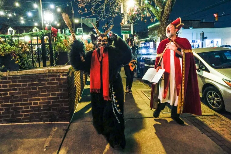 Saint Nicolas, as portrayed by local author Matt Lake, at right, and Krampus, at left, sing Krampus carols on State Street as part of the 2nd annual Krampusfest in Media.