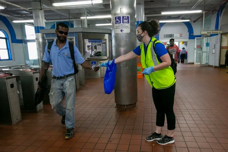 Jessica Mangold, project manager with SEPTA, handed a mask to Justin Leysath as he passed through 69th Street Station in Upper Darby on Aug. 13.
