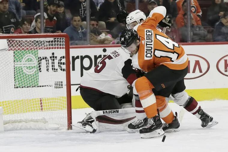 The Flyers' Sean Couturier tries to control the puck with the Coyotes net open.