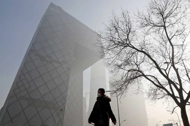 A Chinese woman wears a mask while walking in smog-filled Beijing in January.